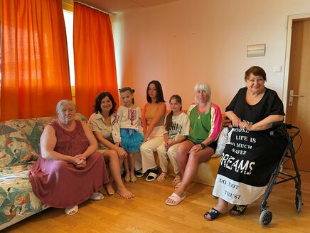 Geflüchtete Familie aus Ukraine auf Couch in Wohnzimmer sitzend